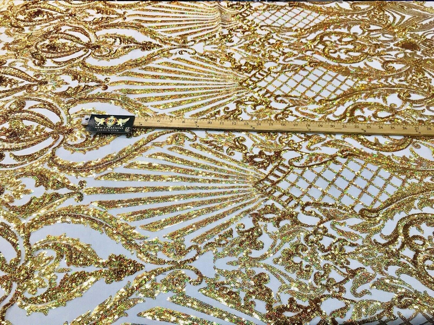 Diseño de lentejuelas de damasco iridiscente dorado en una malla elástica de 4 vías por yarda.