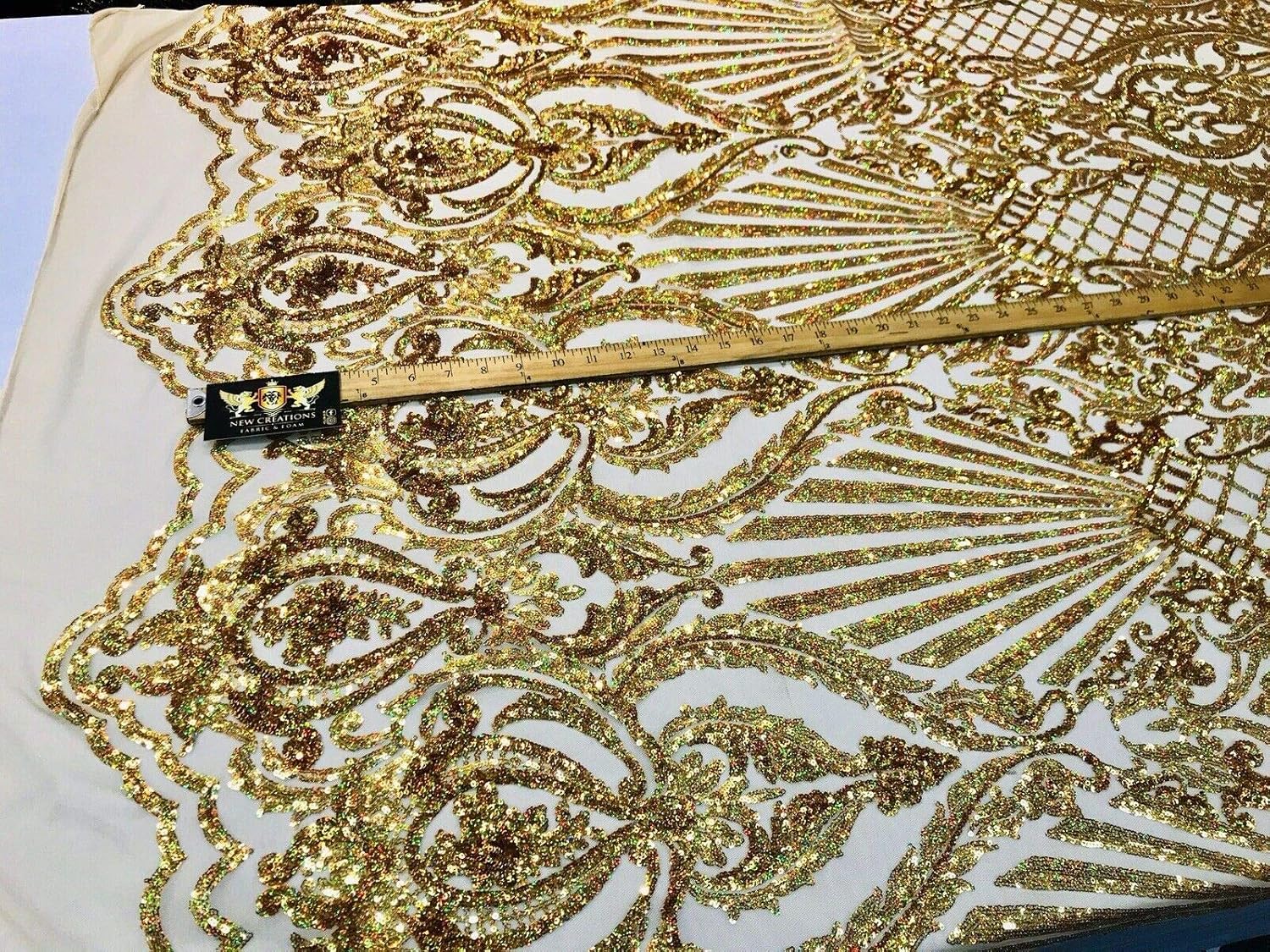 Diseño de lentejuelas de damasco iridiscente dorado en una malla elástica de 4 vías por yarda.