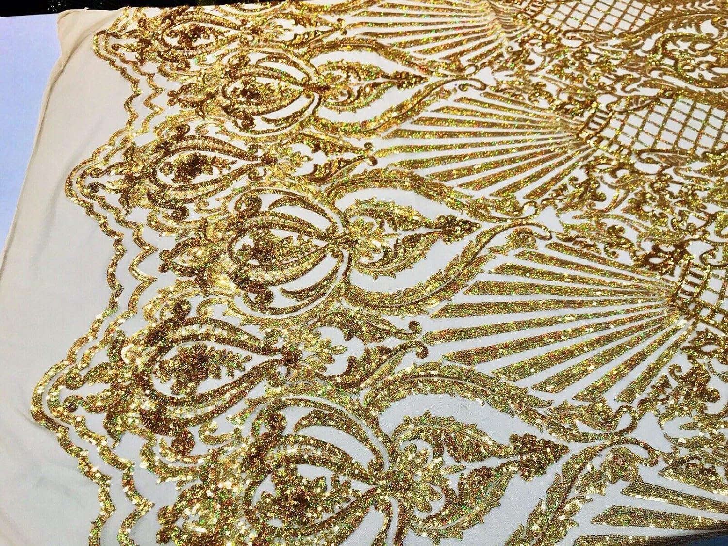 Diseño de lentejuelas de damasco iridiscente dorado en una malla elástica de 4 vías por yarda.